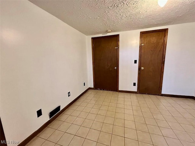 empty room featuring light tile patterned floors and a textured ceiling