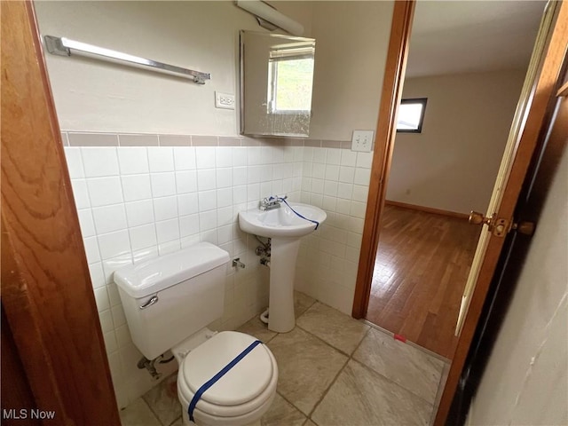 bathroom with wood-type flooring, toilet, and tile walls