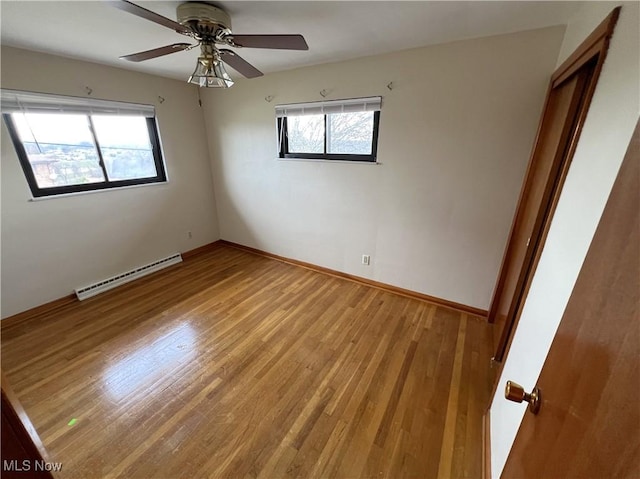 empty room with light hardwood / wood-style floors, plenty of natural light, baseboard heating, and ceiling fan