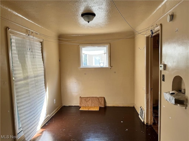 interior space featuring a textured ceiling, baseboards, and wood finished floors