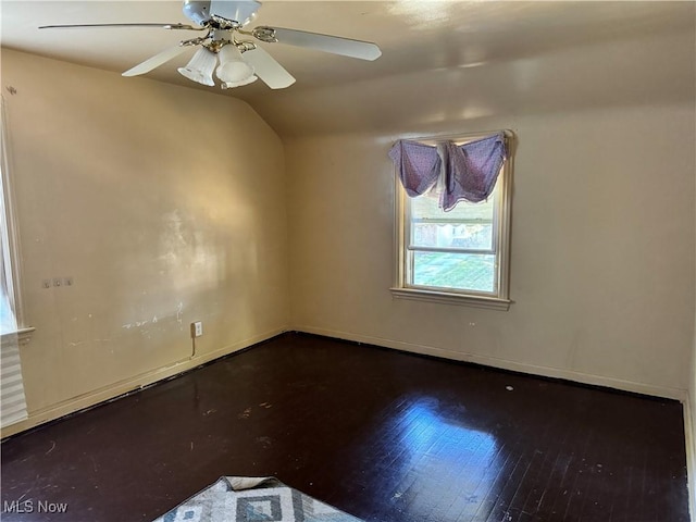 empty room with baseboards, wood finished floors, a ceiling fan, and vaulted ceiling