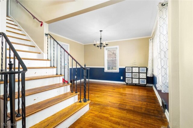 staircase with hardwood / wood-style flooring, an inviting chandelier, and crown molding