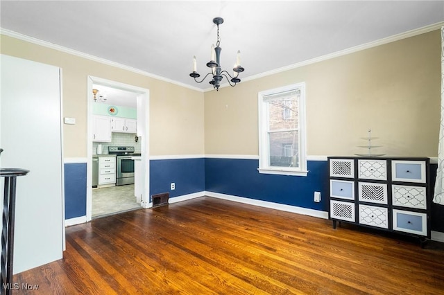 spare room with dark hardwood / wood-style flooring, an inviting chandelier, and crown molding