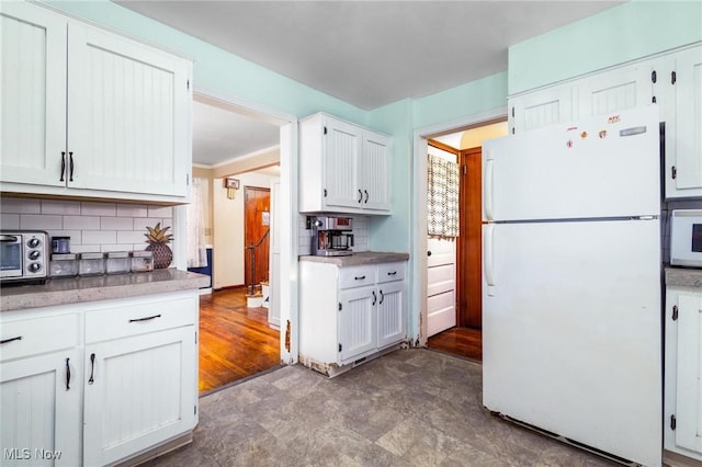 kitchen with tasteful backsplash, white cabinetry, white appliances, and hardwood / wood-style flooring