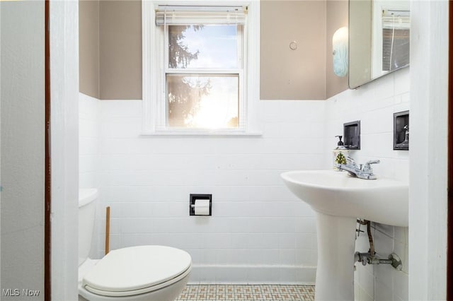 bathroom with toilet and tile walls