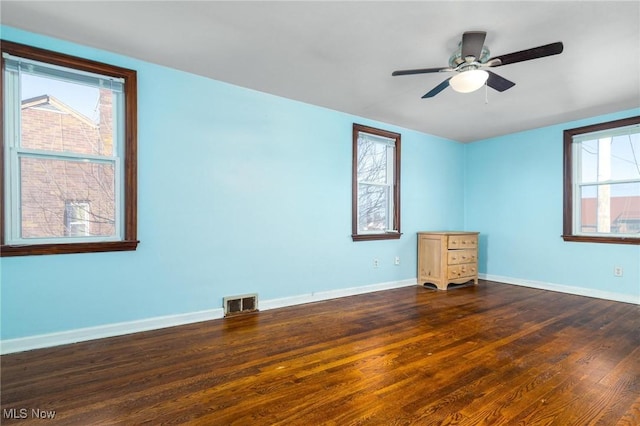 unfurnished room featuring plenty of natural light, ceiling fan, and dark wood-type flooring