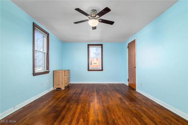 spare room featuring plenty of natural light, ceiling fan, and dark hardwood / wood-style flooring