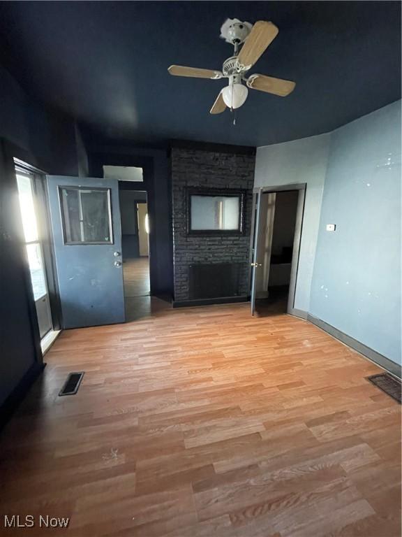 interior space with ceiling fan, wood-type flooring, and a brick fireplace