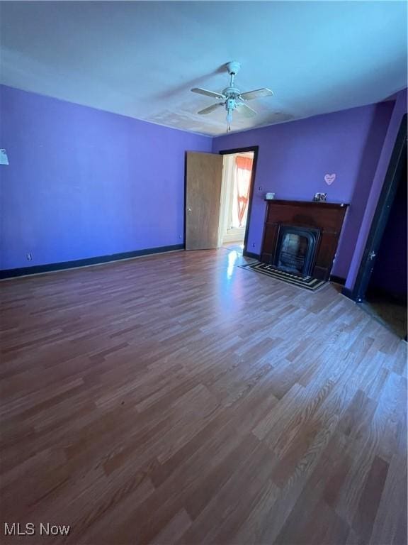 unfurnished living room featuring ceiling fan and dark hardwood / wood-style floors