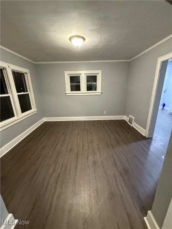 spare room featuring dark wood-type flooring and ornamental molding