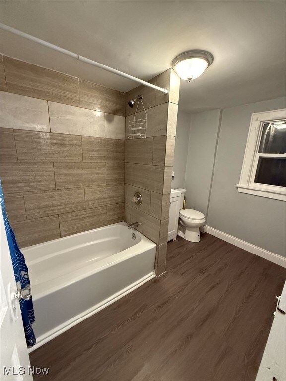 bathroom with toilet, shower / bath combo with shower curtain, and hardwood / wood-style flooring