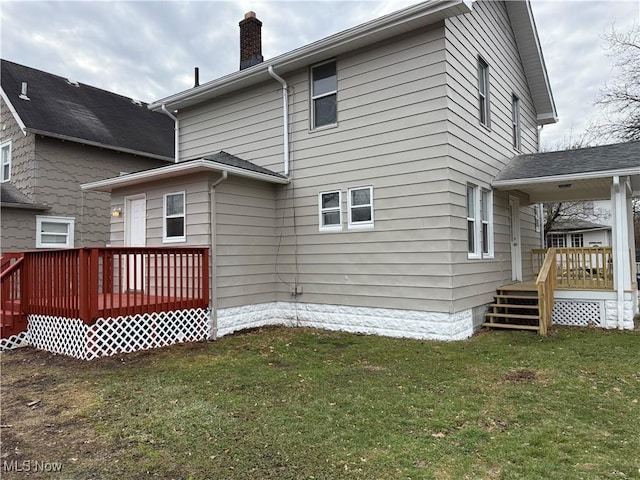 rear view of property featuring a wooden deck and a lawn