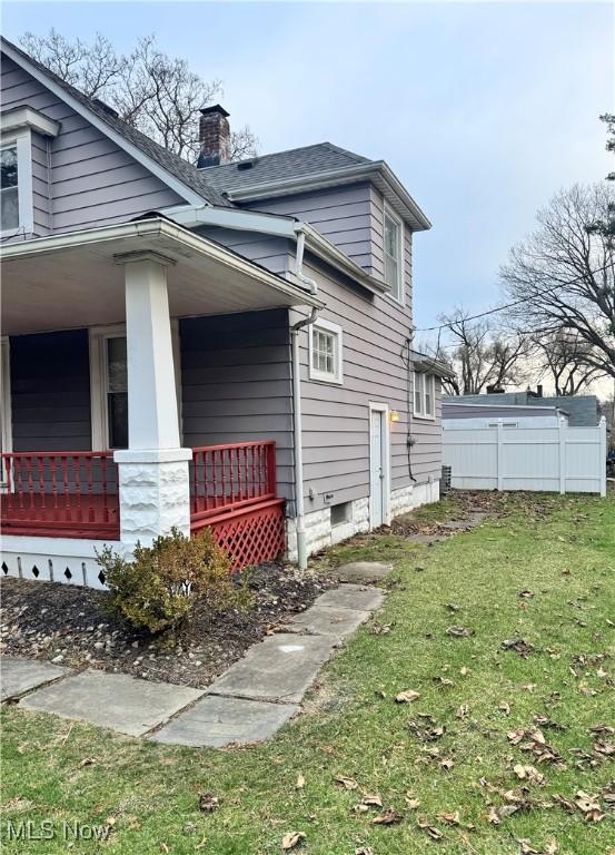 view of side of property featuring a lawn and a porch