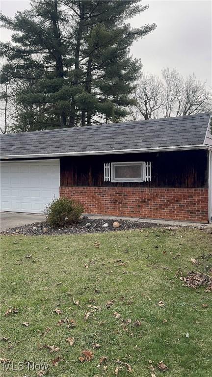 view of side of property featuring a garage and a lawn