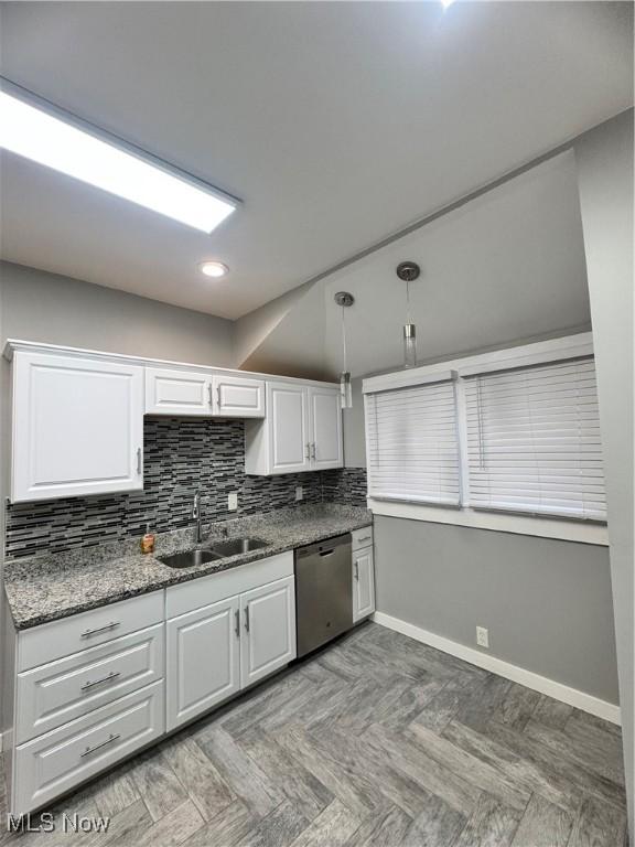 kitchen with pendant lighting, white cabinets, sink, stainless steel dishwasher, and tasteful backsplash