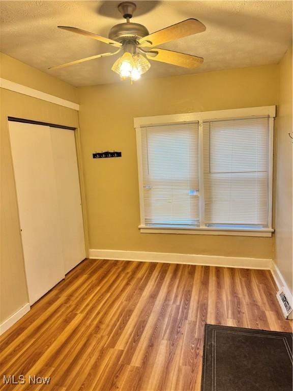 interior space with a textured ceiling, a closet, ceiling fan, and hardwood / wood-style flooring