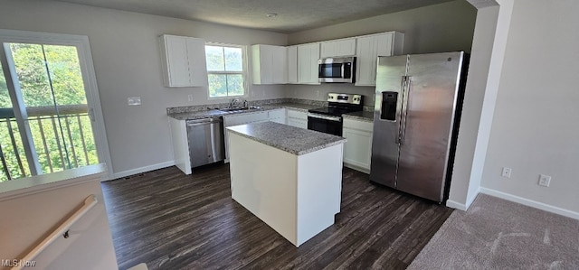 kitchen with stainless steel appliances, dark wood-type flooring, sink, a center island, and white cabinetry