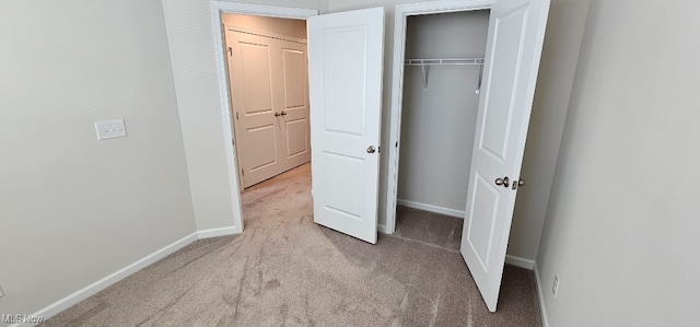 unfurnished bedroom with light colored carpet and a closet