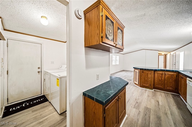 kitchen with vaulted ceiling, washer and dryer, light hardwood / wood-style floors, kitchen peninsula, and a textured ceiling