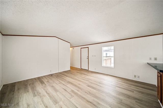 unfurnished living room with crown molding, lofted ceiling, a textured ceiling, and light hardwood / wood-style floors