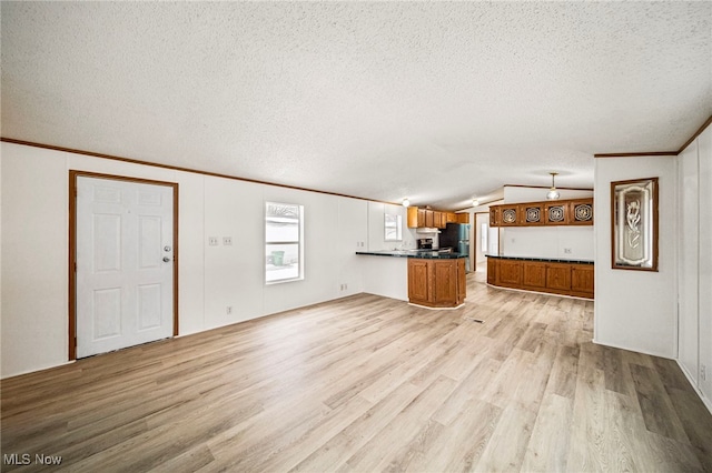 unfurnished living room with vaulted ceiling, ornamental molding, light hardwood / wood-style floors, and a textured ceiling