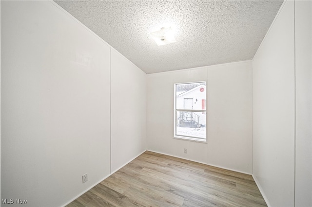 empty room featuring crown molding, a textured ceiling, and light wood-type flooring