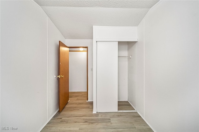 unfurnished bedroom featuring light hardwood / wood-style floors, a closet, and a textured ceiling