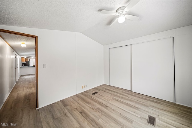 bonus room featuring ceiling fan, vaulted ceiling, light hardwood / wood-style floors, and a textured ceiling