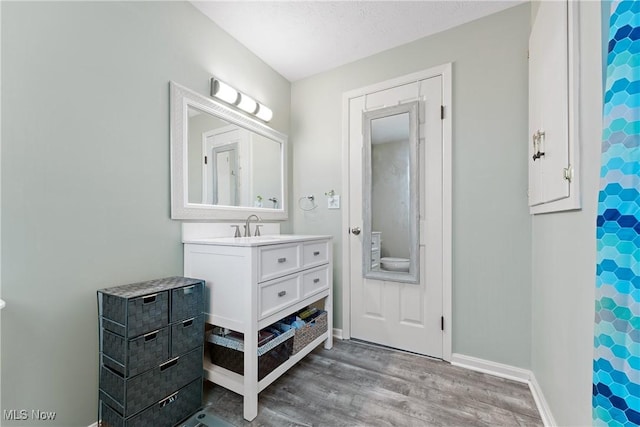 bathroom with vanity, toilet, wood-type flooring, and a textured ceiling