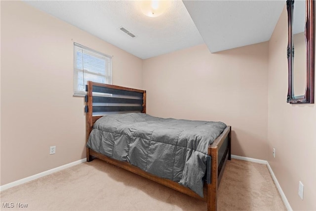 bedroom with light colored carpet and a textured ceiling