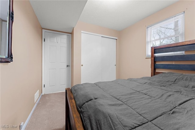 carpeted bedroom featuring a textured ceiling and a closet