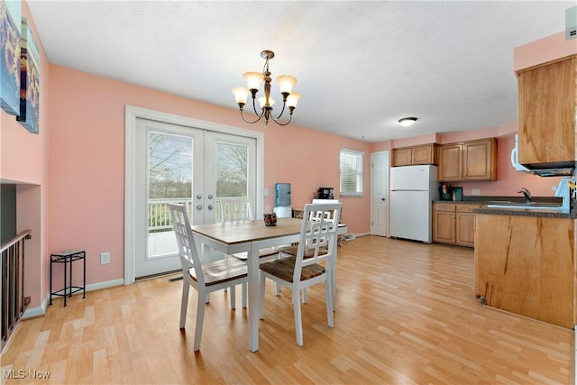 dining area featuring sink, light hardwood / wood-style flooring, french doors, and an inviting chandelier