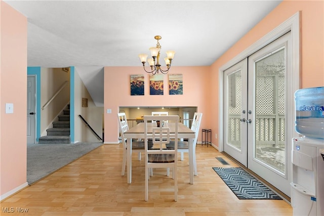 dining space with a chandelier, french doors, and light wood-type flooring