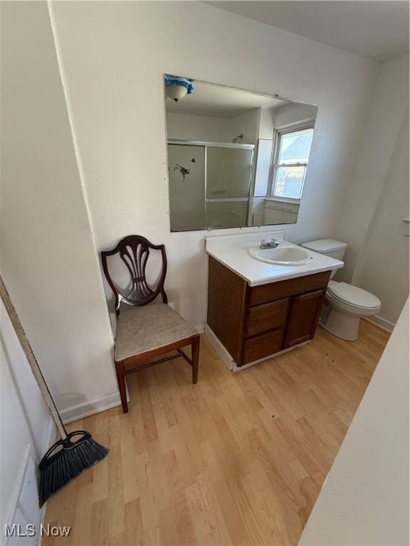 bathroom with a shower with shower door, toilet, wood-type flooring, and vanity