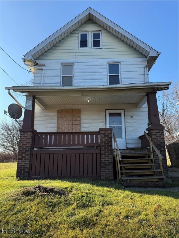 rear view of house featuring covered porch and a yard