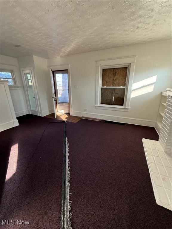 empty room featuring a fireplace, carpet, and a textured ceiling