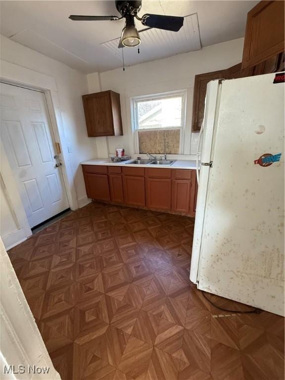 kitchen featuring ceiling fan, white fridge, sink, and dark parquet floors