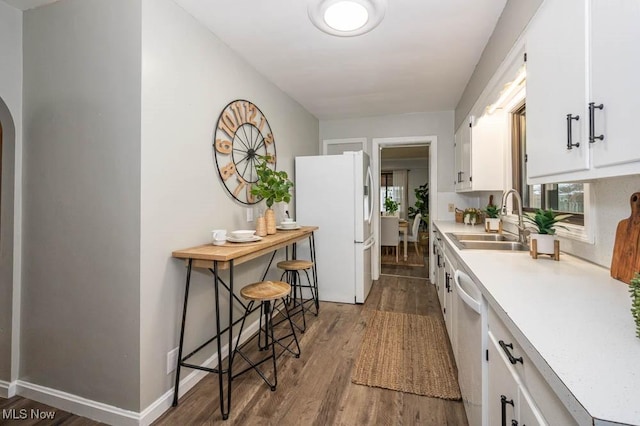 kitchen with stainless steel dishwasher, dark wood-type flooring, sink, white fridge, and white cabinetry