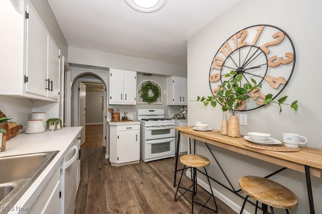 kitchen with white cabinetry, dark wood-type flooring, white range with gas stovetop, and stainless steel dishwasher