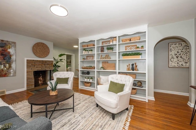 sitting room featuring wood-type flooring and a brick fireplace