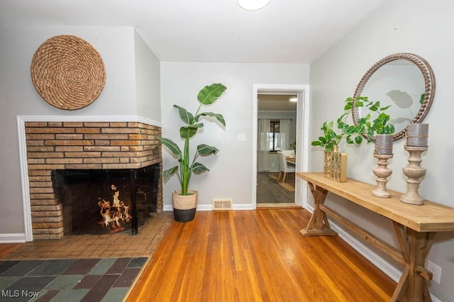 interior space featuring hardwood / wood-style flooring and a brick fireplace