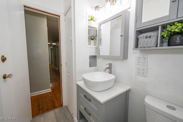 bathroom with hardwood / wood-style floors, vanity, and toilet