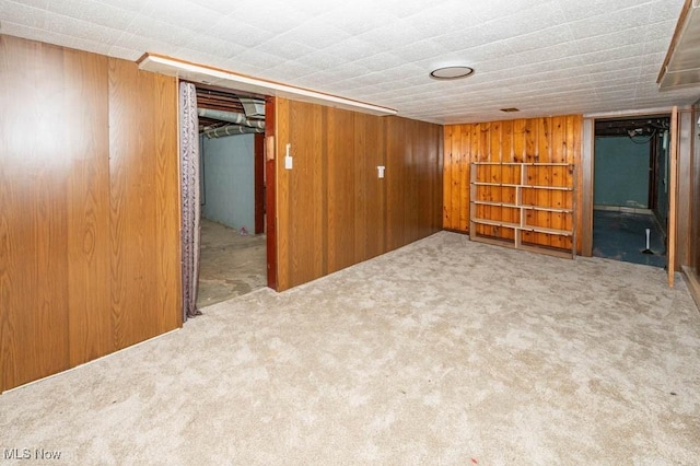 basement featuring light carpet and wooden walls