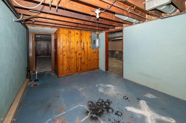 basement featuring wooden walls and electric panel