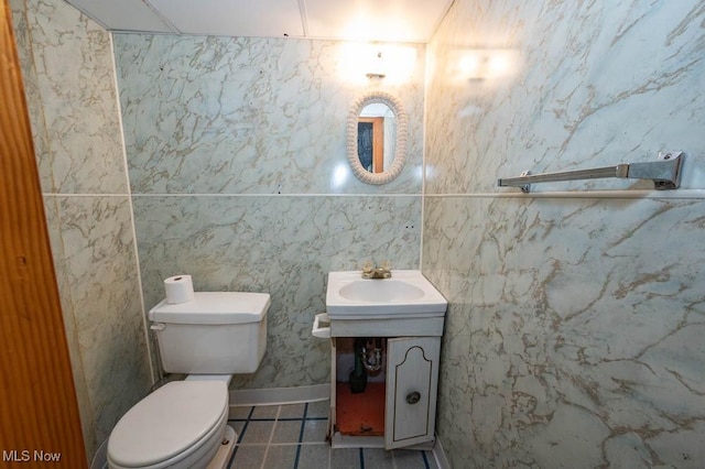 bathroom featuring vanity, toilet, and tile walls