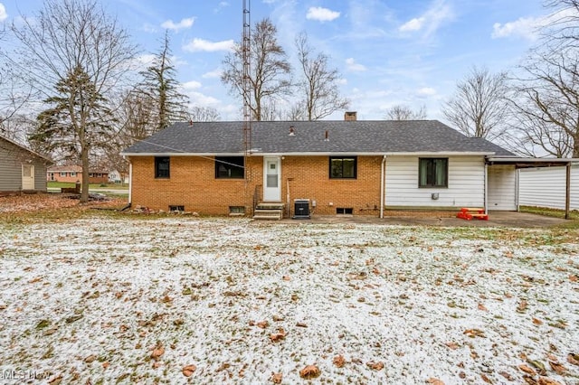 snow covered rear of property with central AC unit and a carport