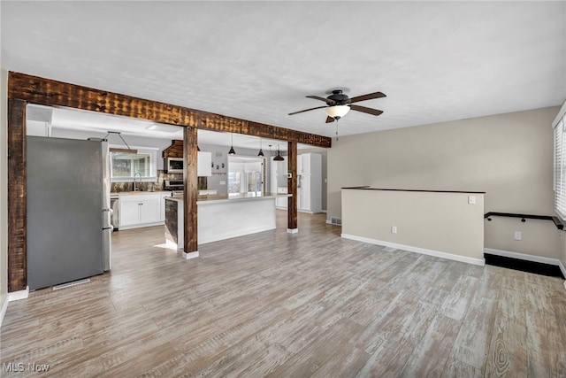 unfurnished living room featuring ceiling fan, sink, and light hardwood / wood-style flooring