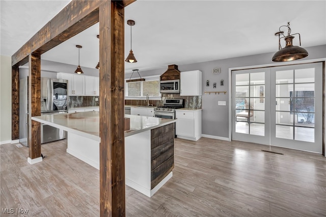 kitchen with white cabinets, light hardwood / wood-style floors, stainless steel appliances, and tasteful backsplash