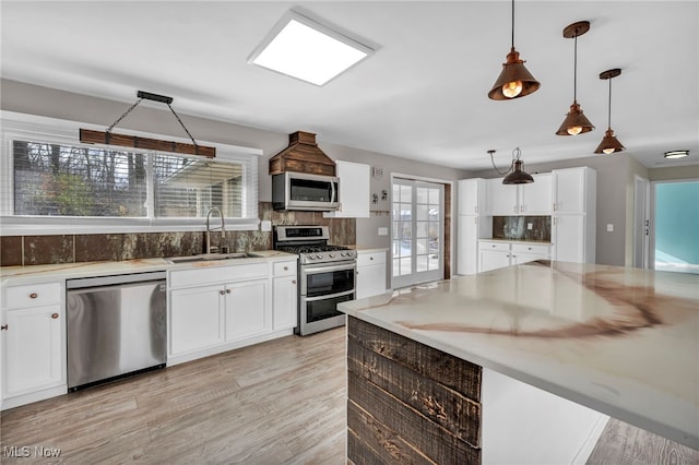 kitchen with white cabinets, pendant lighting, stainless steel appliances, and sink