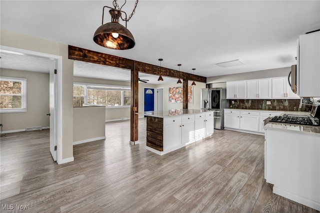 kitchen featuring a center island, a healthy amount of sunlight, decorative light fixtures, and appliances with stainless steel finishes